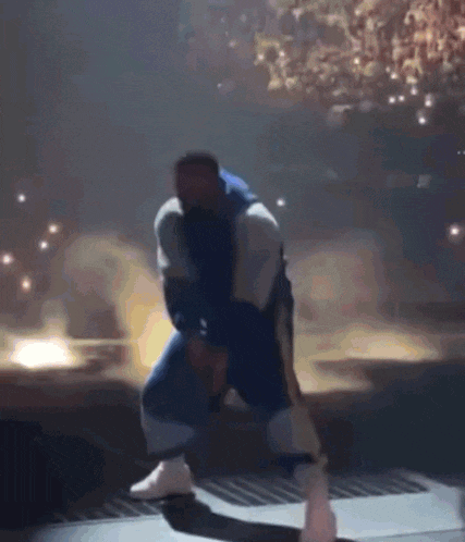 a man in a blue jacket is kneeling on a stage