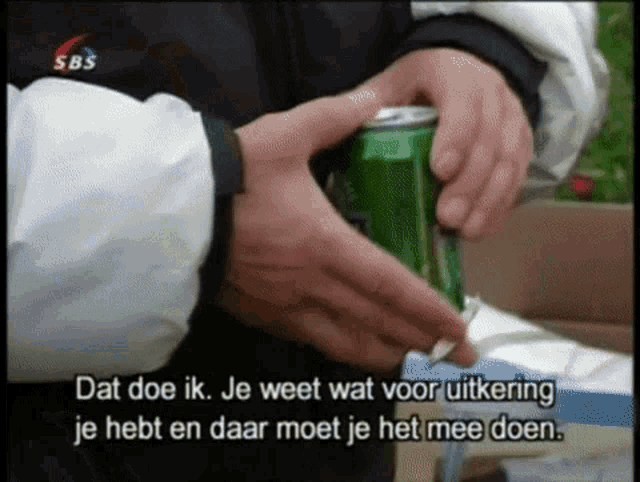 a person is opening a green soda can with sbs written on the bottom