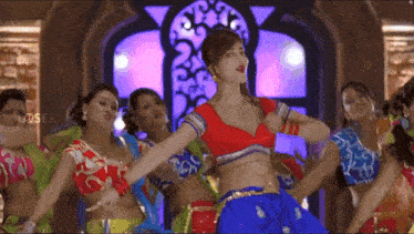 a woman in a red top is dancing in front of a group of women