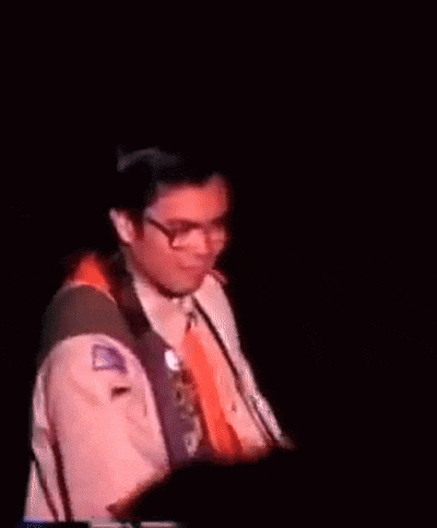 a blurry picture of a man in a suit and tie holding a microphone
