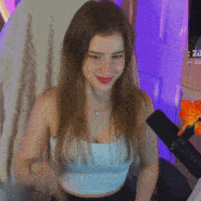 a woman in a white tank top is sitting in front of a microphone and smiling .