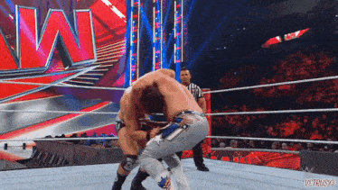 two men are wrestling in a wrestling ring with a referee watching