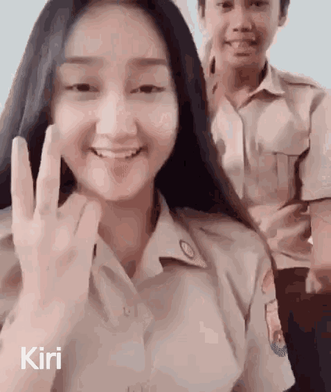 a girl in a school uniform is giving the peace sign