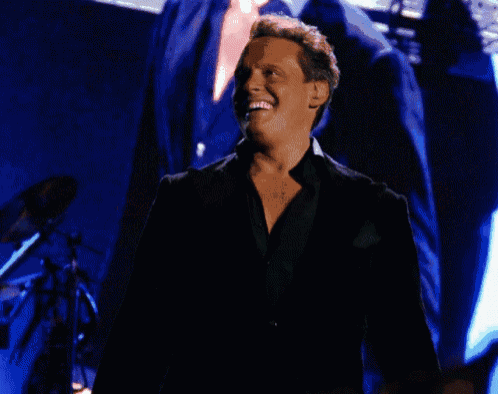 a man in a black suit is smiling in front of a starry background