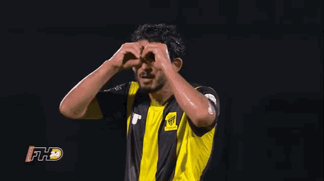 a soccer player is making a heart shape with his hands .