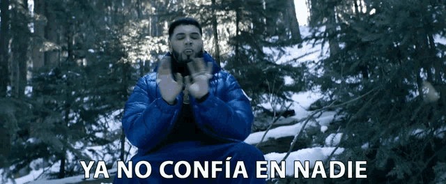 a man in a blue jacket is sitting in the snow with the words ya no confia en nadie written below him