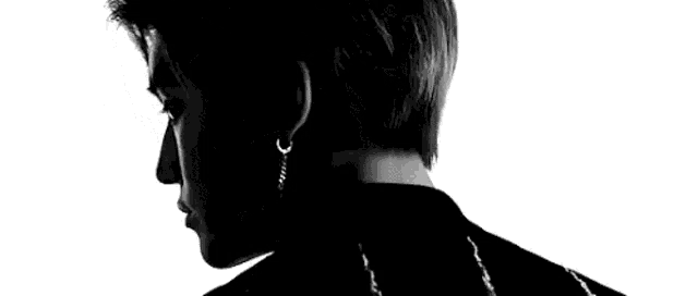 a black and white photo of a young man wearing earrings and a sweater .