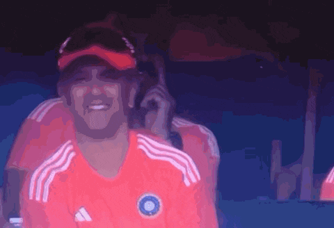 a man wearing a red adidas shirt is talking on a cell phone