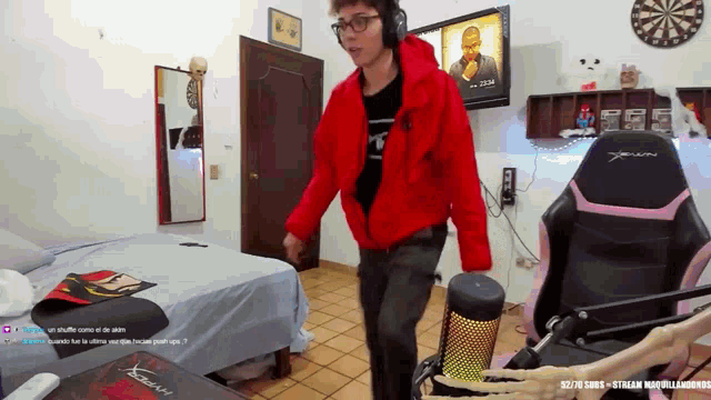 a man in a red jacket is dancing in a room with a skeleton in front of him