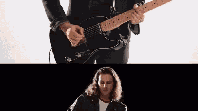 a man with long hair is playing a black electric guitar