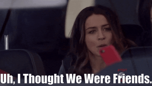 a woman sitting in the back seat of a car looking at her phone with the words " uh i thought we were friends " above her