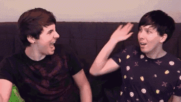 two young men are sitting next to each other on a couch and laughing .