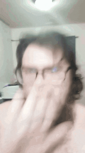 a blurry picture of a man wearing glasses covering his mouth
