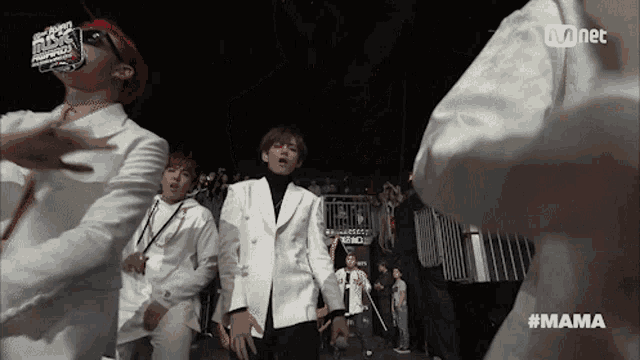 a group of young men are dancing in front of a crowd and a sign that says mama