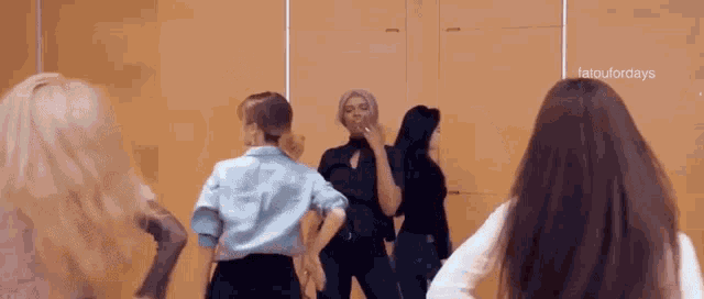 a group of women are dancing in front of a mirror in a room .