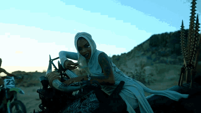a woman in a white dress is sitting on a motorcycle with the number 28 on it