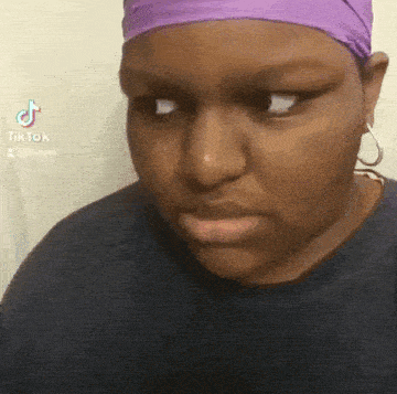 a woman wearing a purple headband and earrings is making a face .