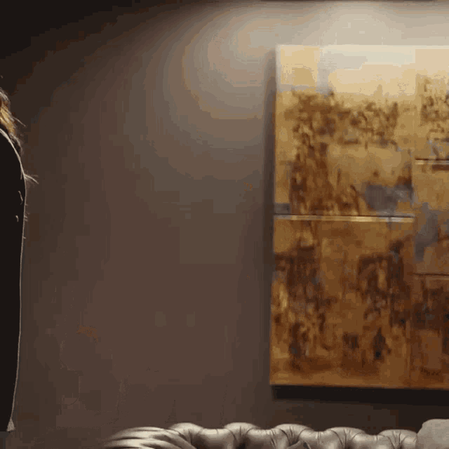 a man in a suit stands in front of a large painting