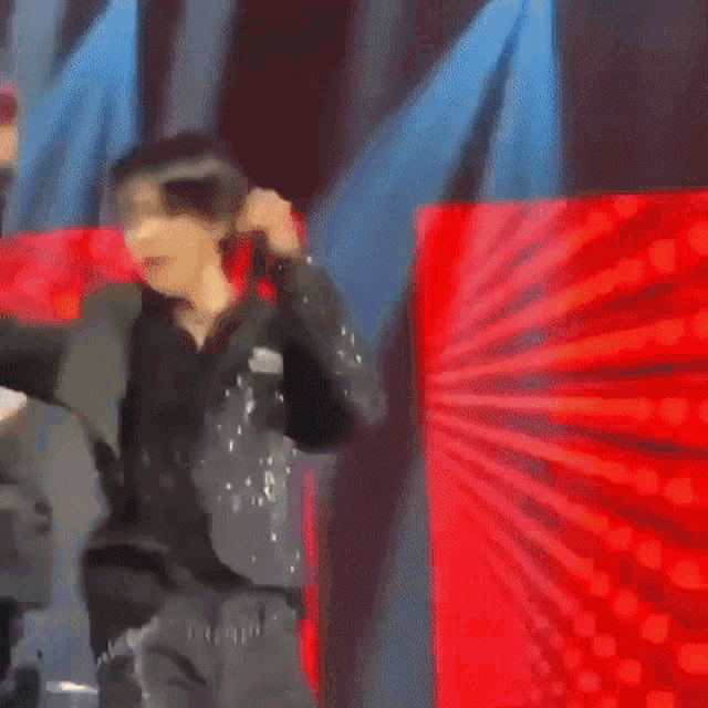 a blurry picture of a person dancing on a stage with a microphone in their hand .