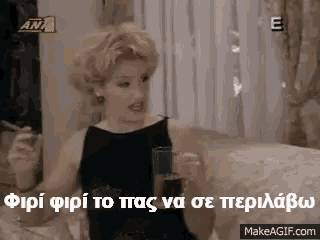 a woman in a black dress is sitting on a couch holding a glass of soda and smoking a cigarette .