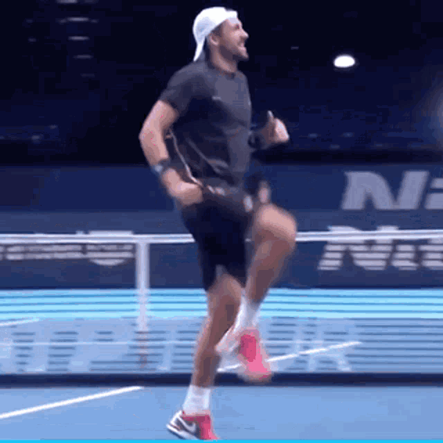 a man is running on a tennis court in front of a sign that says nike