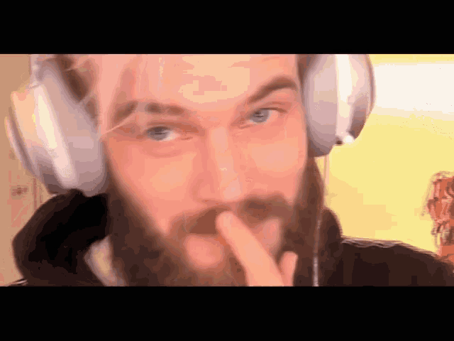 a man with a beard wearing headphones covering his mouth