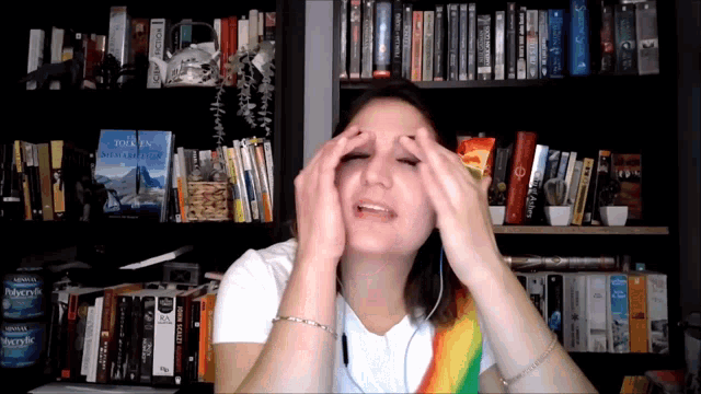 a woman holds her head in front of a bookshelf with a book called tolkien
