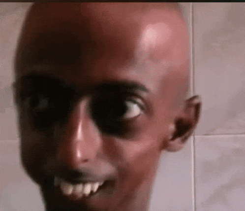 a close up of a bald man 's face with a big smile on his face .