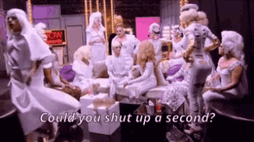a group of people in white clothes are sitting around a table and dancing .