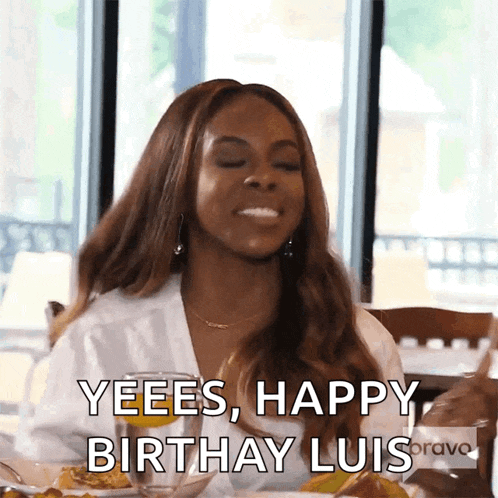 a woman is sitting at a table with a plate of food and a glass of water and says yeees happy birthday luis