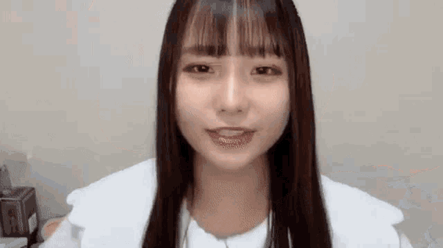 a young girl with long hair and bangs is looking at the camera .