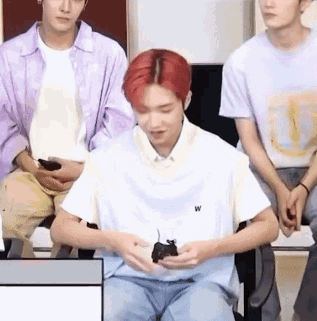 a man with red hair is sitting in front of a group of people holding a mouse in his hands .
