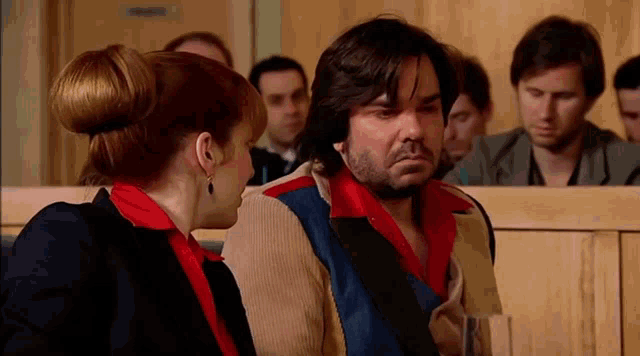 a man and a woman are sitting in a courtroom talking