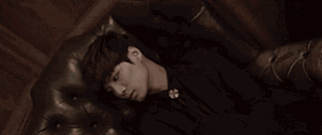 a young man is laying in a chair with his head on the armrest .