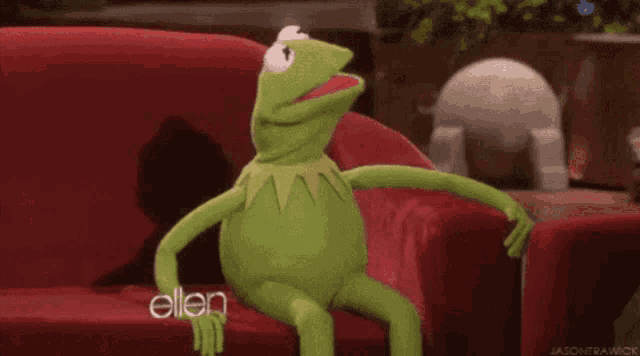 kermit the frog from sesame street is making a funny face with a heart in his mouth .
