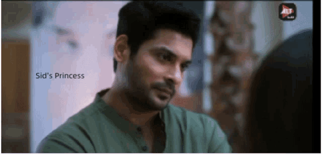 a man in a green shirt is looking at a woman with sid 's princess written on the bottom of the screen
