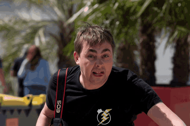 a man wearing a black eos camera strap