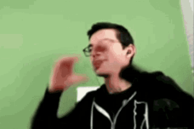 a man wearing glasses and a black jacket is making a funny face .