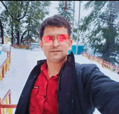 a man wearing red sunglasses and a red shirt is taking a selfie in the snow