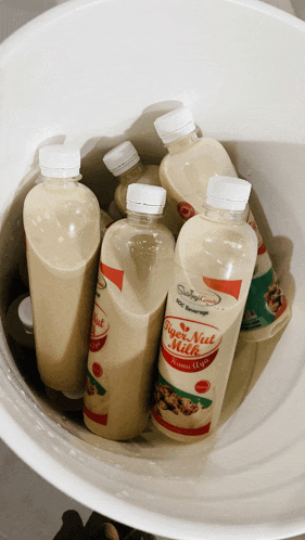 several bottles of tiger nut milk are in a white bucket
