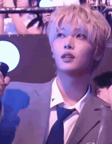 a man in a suit and tie is holding a microphone and looking up at something .