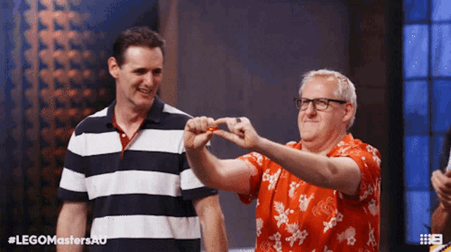 two men are standing next to each other and one of them is wearing a red shirt