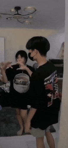 a boy wearing a mask is standing next to a girl in a room