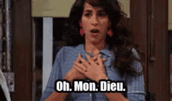 a woman in a blue shirt is holding her hands to her chest and saying oh mon dieu .