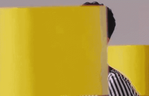 a man wearing a striped shirt and tie is standing in front of yellow blocks .