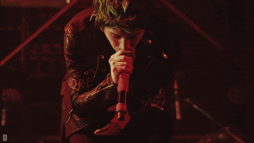 a man singing into a microphone with the word more written on his sleeve