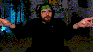 a man with a beard is sitting in a dark room with his hands outstretched