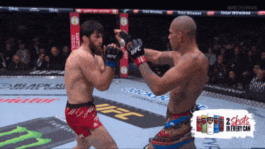 two men fighting in a ufc ring with a monster energy drink in the background