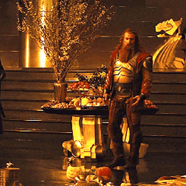 a man with a beard is standing in front of a table full of fruits and vegetables
