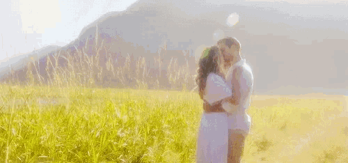a man and a woman are hugging each other in a field .